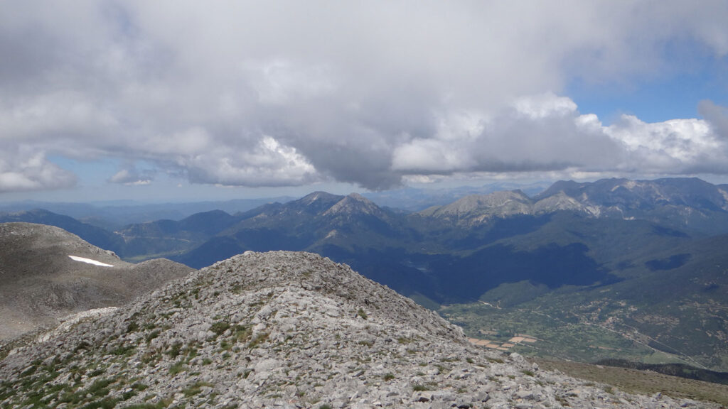 View from the summit of Kyllini, with rocky slopes in the foreground, and other mountain ranges in the background.