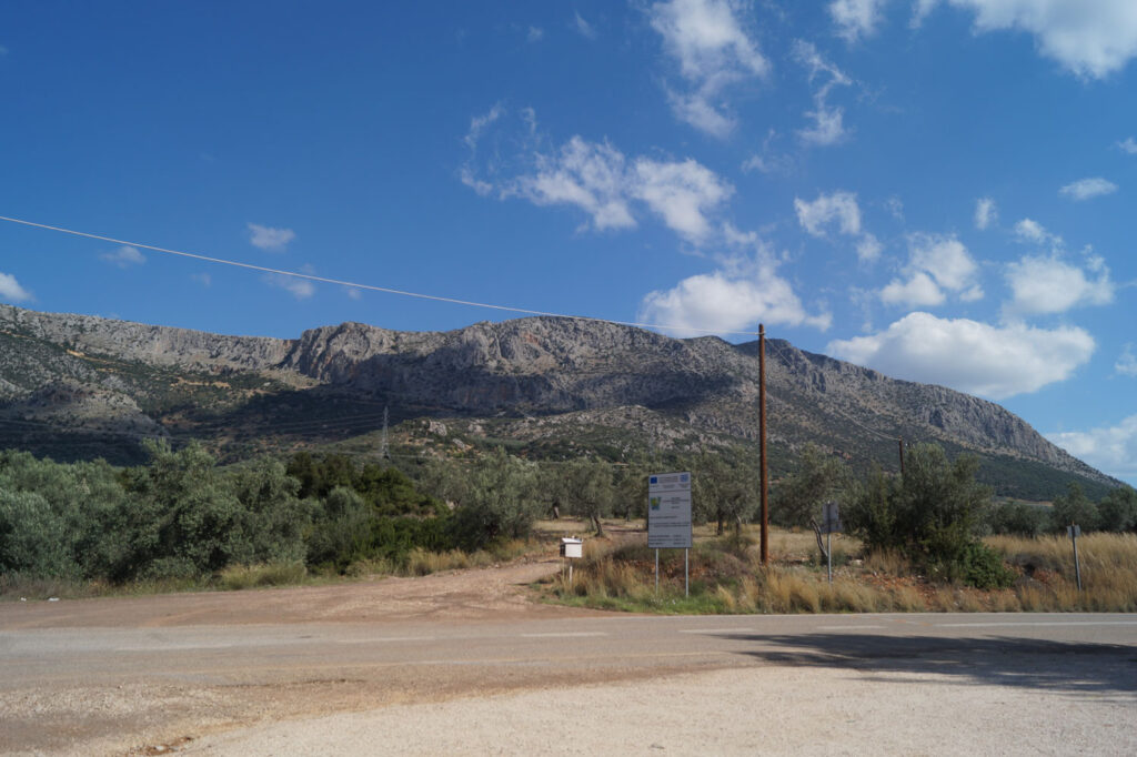 View of Mount Arachnaio from the church of Agios Ioannis Theologos, with road in foreground, mountain ridge in background.