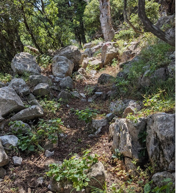 Rough uphill track between hills and rocks.
