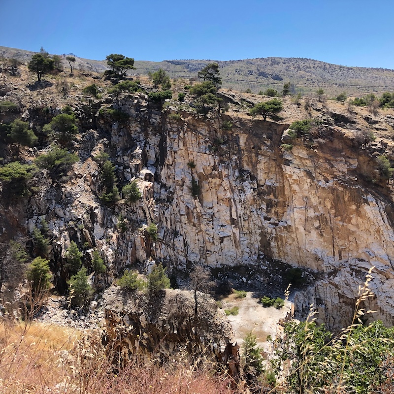 Sheer and tree-covered cliffs of abdandoned quarry, viewed from above.