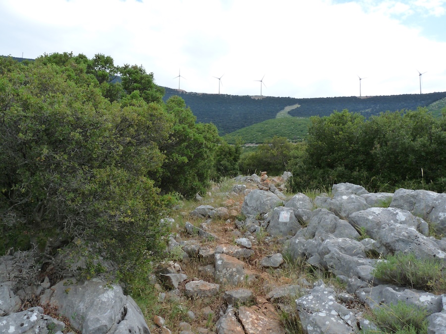 rocky path with summit ridge and wind turbines in distance