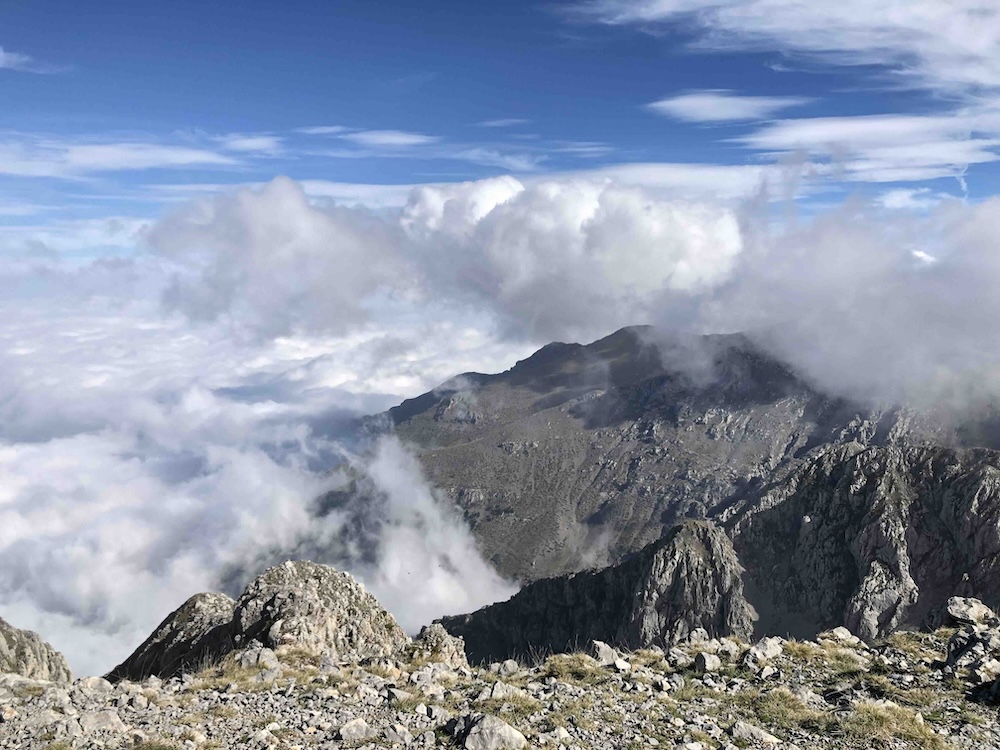 view down from mountain summit to cloud and cliffs below