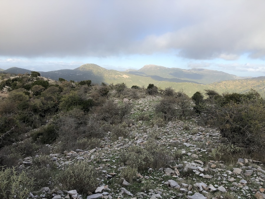 View of distant mountain peaks and rocky hillside in foreground