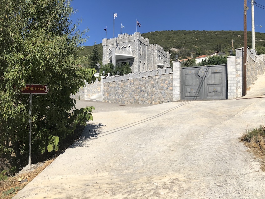 Road junction with houses and hill in the background.