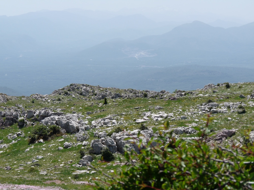 View of rocky ground in foreground and mountains in the distance.